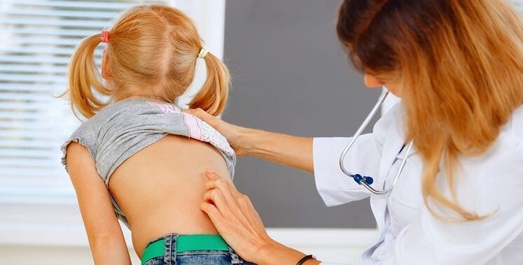 doktor na sinusuri ang likod ng isang bata para sa sakit sa ibabang bahagi ng likod
